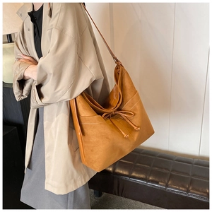 Détail du grand sac cabas en daim caramel avec coutures blanches et nœud décoratif