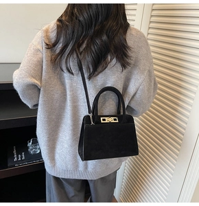 Model wearing black suede handbag with golden clasp, showing minimalist style and texture