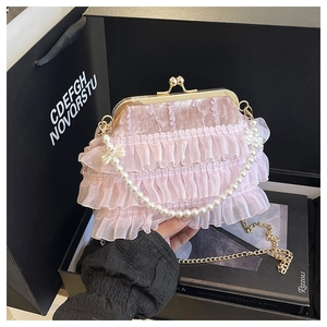 Détail du sac en velours rose avec volants en dentelle, poignée perle et fermoir doré