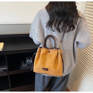 Détails du sac seau en daim jaune avec fermeture à cordon et bordures marron