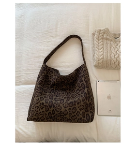 Detail view of large leopard print canvas tote bag on white bedding with iPad for size reference