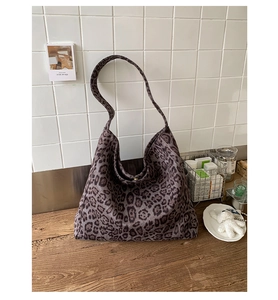 Detailed view of leopard print hobo bag texture and wide strap on a wooden desk
