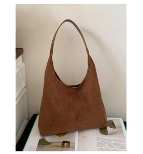 Detail of caramel brown suede hobo bag with vertical stitching and smooth matte texture