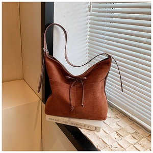 Détail du sac à bandoulière en daim marron foncé avec cordon et nœud de style vintage