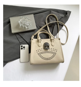 Gros plan sur un sac cabas en cuir crème avec crâne métallique et clous décoratifs