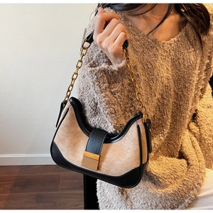Detail of hobo bag featuring black leather, beige suede, and chunky gold chain strap