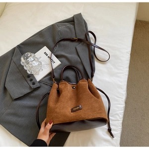 Détail d'un sac seau en daim marron avec base en cuir et fermeture à cordon