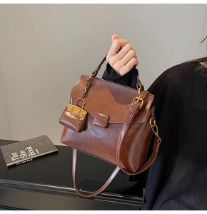 Detail of vintage brown oil wax leather handbag with golden buckle and mini charm