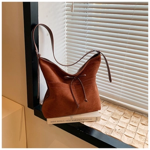 Détail du sac hobo en daim caramel avec nœud de serrage et surpiqûres décoratives blanches
