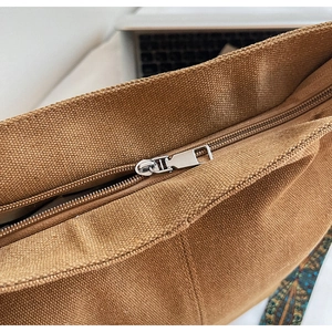 Detail of high-quality brown canvas texture and durable silver metal zipper on tote bag