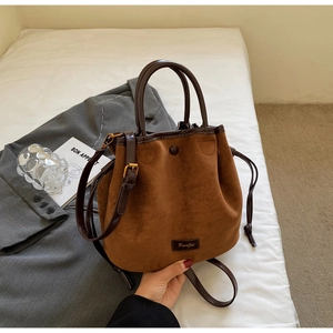 Détail du sac seau en daim caramel avec cordon de serrage et plaque logo gravée