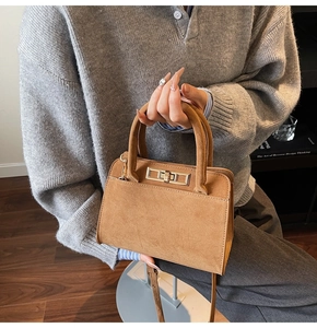Detail of brown suede tote bag featuring a golden rectangular twist lock and top handles