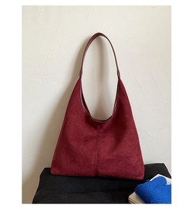 Detail of burgundy suede-textured hobo tote bag against a minimalist cream background