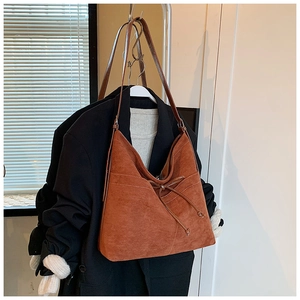 Détail d'un sac cabas en daim caramel avec nœuds coulissants sur un manteau en laine noir