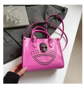 Détail d'un sac cabas rose vif avec un ornement tête de mort et des rivets argentés