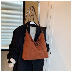 Détail de la texture en daim marron et du nœud sur le grand sac fourre-tout