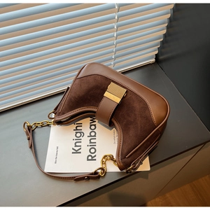 Close-up of contrast brown suede shoulder bag with gold buckle and chain strap