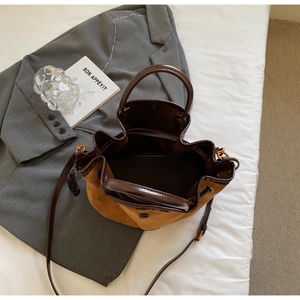 Vue détaillée du sac seau en daim marron avec anses en cuir et fermeture magnétique