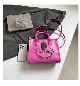 Détail du cabas rose avec relief de crâne noir et clous sur fond de tissu gris