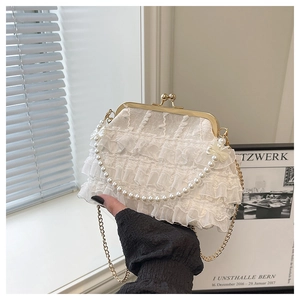 Détail d'un sac en dentelle blanche avec volants, anse en perles et fermoir doré chic