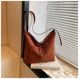 Détail du sac cabas en daim marron foncé avec coutures blanches et cordon à nœud