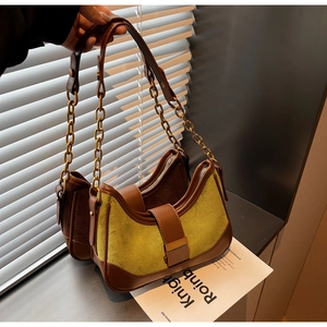 Detail of retro color-block shoulder bag with gold chain strap and green suede texture