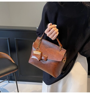 Detail of vintage brown leather handbag with gold hardware and mini charm accessory