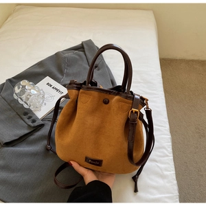 Détail du sac seau en daim caramel avec base en cuir et garnitures dorées élégantes