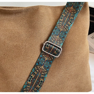 Detail of adjustable ethnic style wide strap on a brown canvas bucket shoulder bag