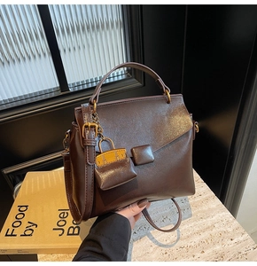 Detail view of smooth dark brown leather handbag with magnetic snap and mini bag charm
