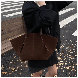Brown suede tote bag with fan-shaped structure shown in an autumn street setting