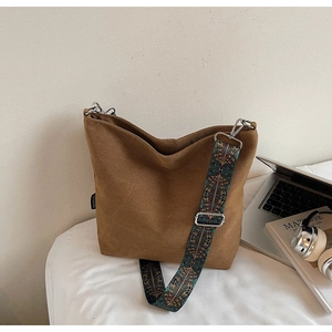 Detail view of brown suede bucket bag with vintage geometric pattern wide strap