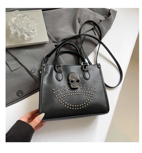 Détail du sac cabas noir avec emblème de crâne en métal et décorations de clous argentés