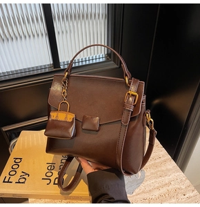 Detailed view of deep brown vintage leather handbag with miniature charm and gold hardware