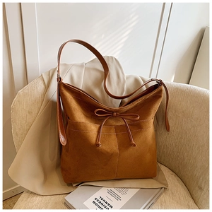 Gros plan du sac cabas en daim caramel avec nœud et doubles poches avant cousues