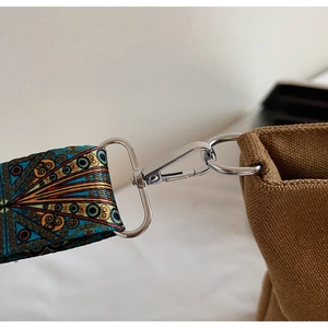 Detailed macro view of ethnic patterned strap and silver metal buckle on brown canvas bag