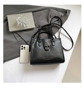 Détail d'un sac cabas noir avec emblème de crâne argenté et décorations en rivets