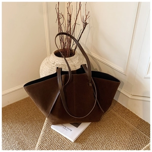 Macro shot of dark coffee suede tote bag showing texture on straw rug background