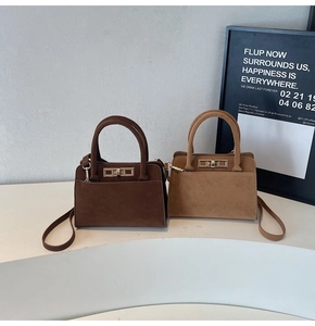 Detail of minimalist suede handbags in dark coffee and khaki with golden metal buckles