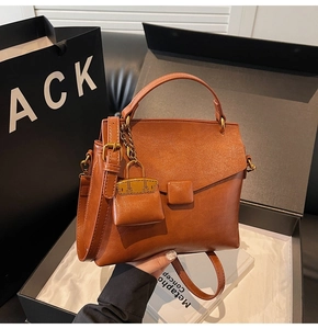 Detailed view of brown retro leather handbag with square lock and mini bag charm