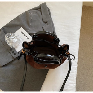 Vue de dessus d'un sac seau en daim marron foncé avec anse en cuir noir et fermoir aimanté