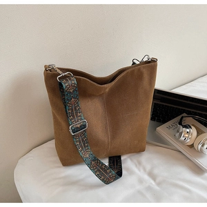Brown bucket bag detail showing a vintage ethnic embroidered strap and suede texture