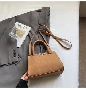 Detail view of brown faux suede tote bag with gold twist lock and stylish top handle
