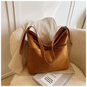 Détail du grand sac cabas en daim marron avec nœud décoratif et bandoulière réglable