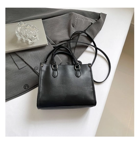 Sac fourre-tout noir structuré avec rivets argentés et texture cuir sur bureau minimaliste
