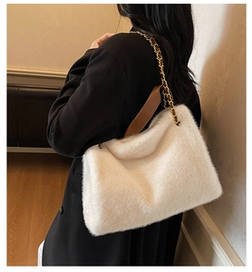 Close-up of fluffy white faux fur shoulder bag with gold chain and leather shoulder strap