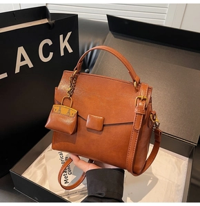 Detail view of brown vintage PU leather square handbag with mini charm on a luxury gift box