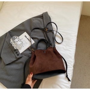 Détail du sac seau en daim rétro avec fermeture à cordon et lanières en cuir noir