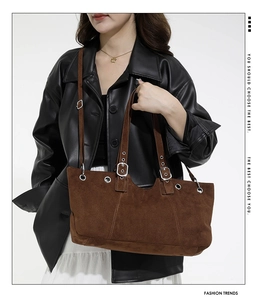 Detail of dark brown suede tote bag with silver eyelets on leather jacket model