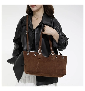 Detailed side view of brown suede tote bag with silver eyelets and adjustable buckle strap